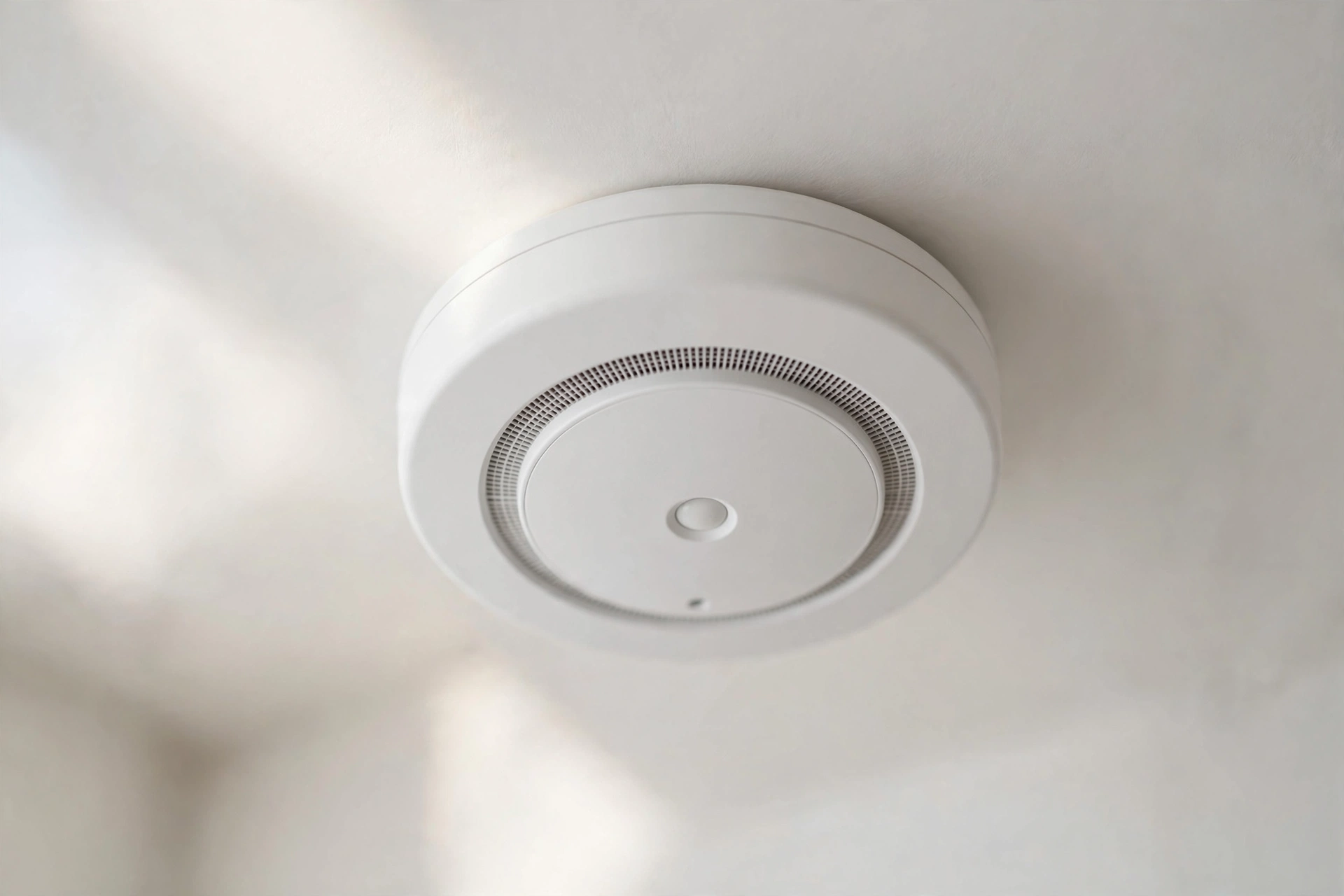 Close-up of a smart smoke detector on a white ceiling